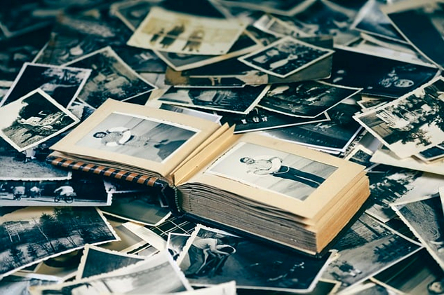 ένα μάτσο παλιές φωτογραφίες και ένα βιβλίο που περιέχει παλιές φωτογραφίες