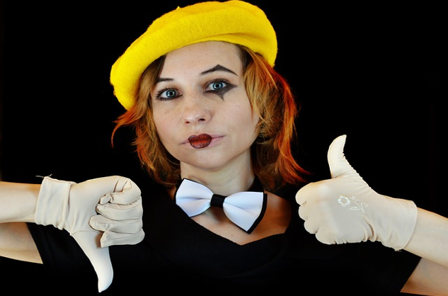 一個化著小丑般妝容的女人，做出豎起大拇指和向下的手勢