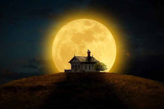 full moon filling the sky behind a house