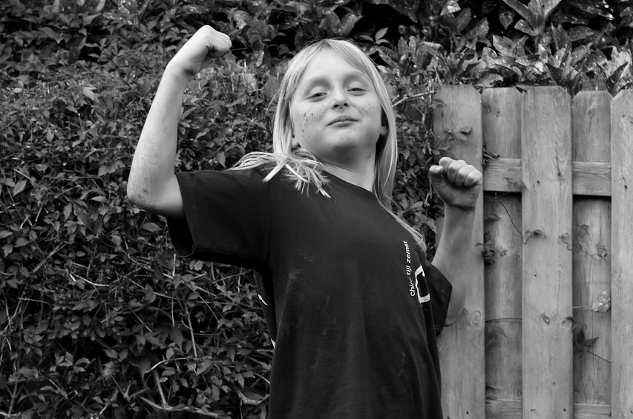 young girl in a proud stance flexing her muscles