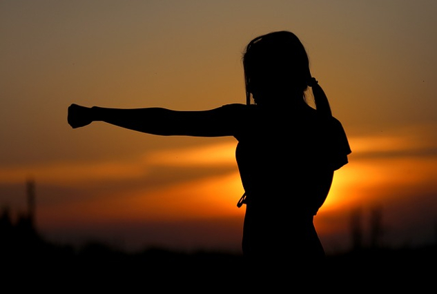 young woman practicing karate outside at sunset