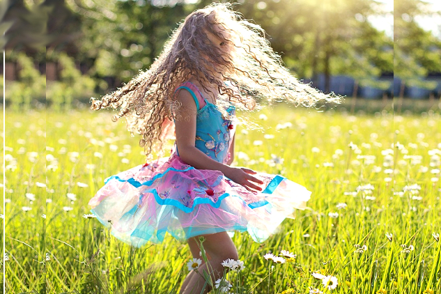 young girl dancing and twirling outside in a meadow