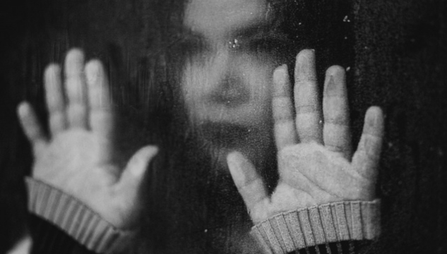 Imagen borrosa de una mujer con las manos extendidas sobre una ventana. Imagen de Kleiton Santos en Pixabay.