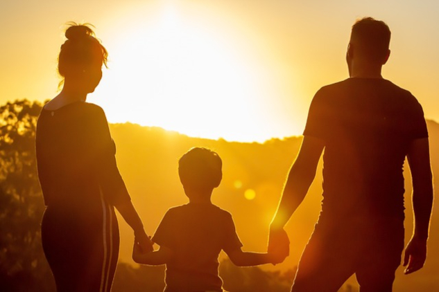 A family standing holding hands in front of the rising sun. Image by s05prodpresidente from Pixabay.