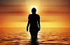 wanita berdiri di lautan melihat matahari terbit