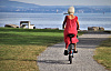 سفید بالوں والی ایک بزرگ خاتون اور سرخ لباس میں سائیکل پر سوار