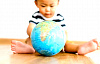 کودکی که روی زمین نشسته و با کره زمین بازی می کند