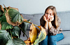 γυναίκα που κάθεται σε έναν καναπέ κοιτάζοντας ένα πολύ ανθυγιεινό φυτό σπιτιού