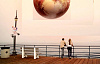 cuplu care se uită la o sferă enorm de mărită a lui Pluto