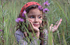 ung flicka i ett fält av höga gräs och vilda blommor