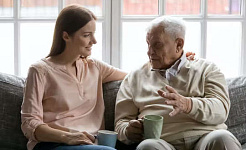 en äldre man pratar med en ung vuxen över en kopp te