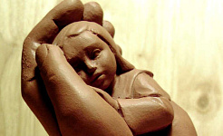 एक सहायक हाथ में पकड़े हुए एक बच्चे की मिट्टी की मूर्ति