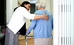 مقدم رعاية يساعد امرأة مسنة على المشي