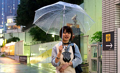 Gadis muda yang tersenyum berjalan dengan payung terbuka