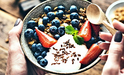 A woman eats a yogurt bowl filled with fruit