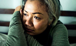 A woman sitting in bed leans on her arms