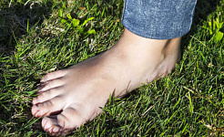 kuva ihmisen paljaasta jalasta seisomassa nurmikolla