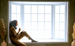 زنی که در یک پنجره خلیج نشسته است