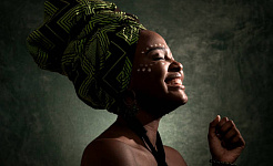 Afrykańska kobieta nosząca nakrycie głowy z zamkniętymi oczami i uśmiechem