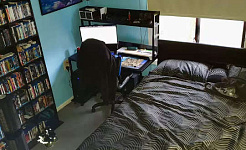 спальня з комп'ютером і письмовим столом прямо біля узголів'я ліжка