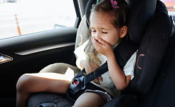 child experiencing motion sickness in a car seat