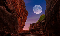 une pleine lune entourée de roche rouge