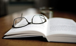 یک کتاب باز با یک جفت عینک روی آن