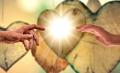 két kéz nyúlik egymás felé egy fényesen csillogó szív előtt