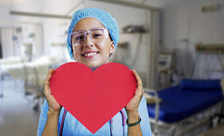 glimlachende verpleegster die een papier omhoog houdt dat in een hartvorm is uitgesneden