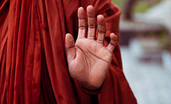 راهب در حالی که دستش را با حرکت مودرا بالا گرفته است
