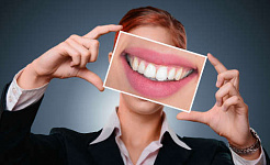 زنی که عکس بزرگ شده دندان هایش را در دست گرفته است
