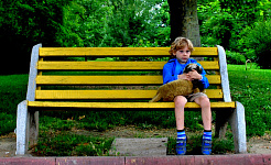 ペットを抱えてベンチに座っている少年