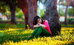 uma jovem sentada e descansando contra uma árvore