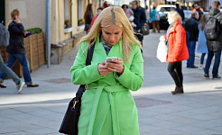 زنی در خیابان با دقت به تلفن خود نگاه می کند