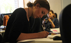 kvinna som sitter vid ett skrivbord och arbetar medan någon i bakgrunden inte arbetar