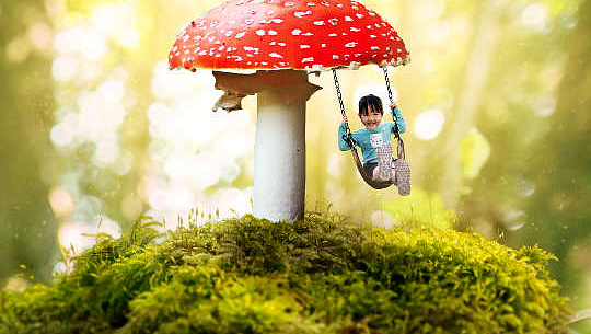 uma criança em um balanço entregando de um enorme cogumelo vermelho