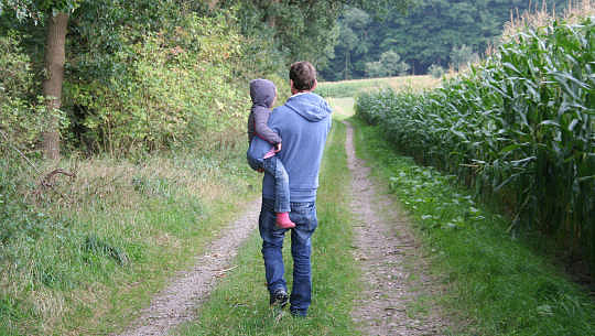 ayah memegang anak lelaki dalam pelukannya dan berjalan di jalan