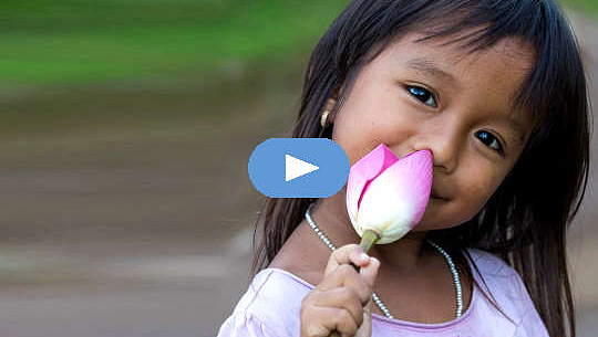 smilende ung jente som holder en uåpnet lotusblomst
