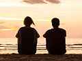 dua orang duduk di tepi lautan