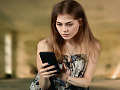 молода жінка дивиться на щось на своєму мобільному телефоні