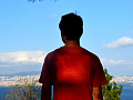रोशनी बिखेरते हृदय वाला एक युवक एक शहर की ओर देखने वाली पहाड़ी पर खड़ा है