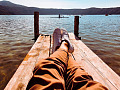 a man laying back on a dock, relaxing