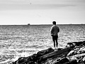 Immagine di un uomo in piedi su alcune rocce che guarda l'acqua. Foto di Davide Dalese da Pixabay.
