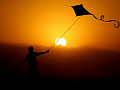 un niño volando una cometa bajo el sol brillante