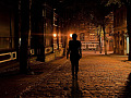 persoon wat alleen in 'n donker straat loop