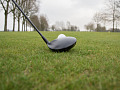 gambar jarak dekat dari tongkat golf yang terletak tepat di depan bola golf