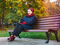 秋日坐在公園長椅上微笑的女人