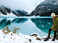 wanita muda berdiri di salju di sebelah danau