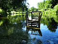 una silla de mimbre en las tranquilas aguas de un río cerca de la orilla del río