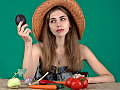 Eine Frau mit einer Auswahl an frischem Gemüse vor sich und einer Avocado